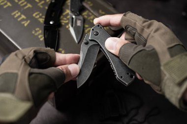 Katlanan bıçakla taktik eldiven giyen adam..