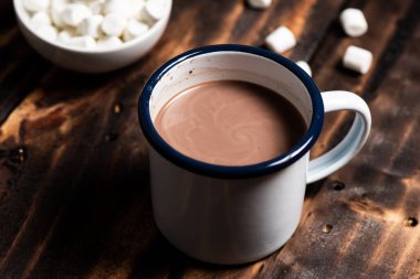 Beyaz diş mineli bardakta sıcak kakao ve arka planda marşmelov..