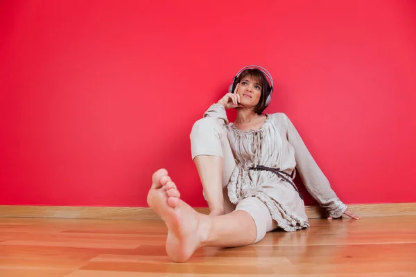 自宅の床に座ってヘッドフォンで音楽を聴く女性 — ストック写真