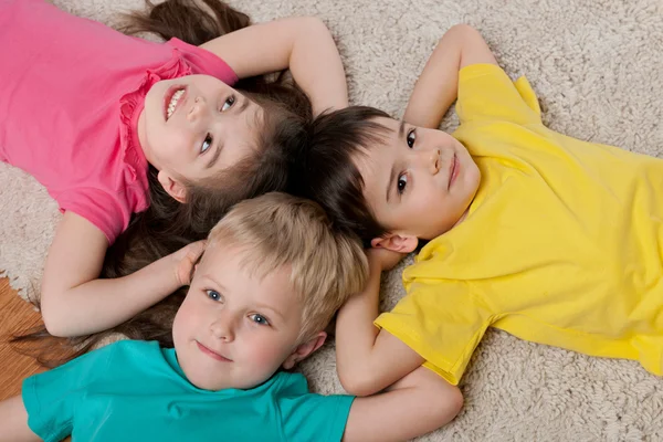 Tre glada barn på vita mattan — Stockfoto
