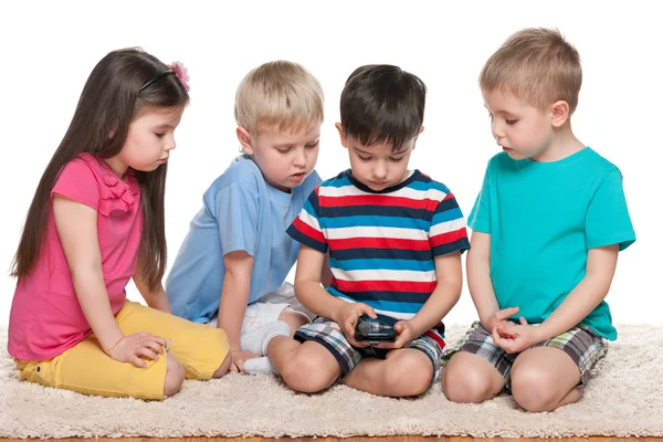 Czworo dzieci z gadżetu na dywanie — Zdjęcie stockowe