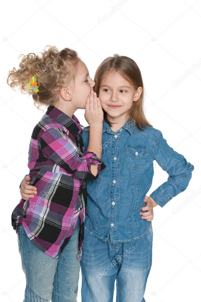 Little girl whispers something to her friend
