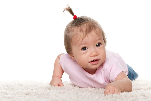 Schattige babymeisje op de witte loper — Stockfoto