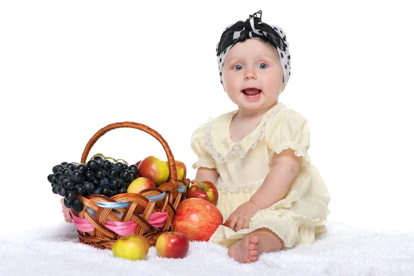 Meisje van de baby in de buurt van een mandje met groenten — Stockfoto