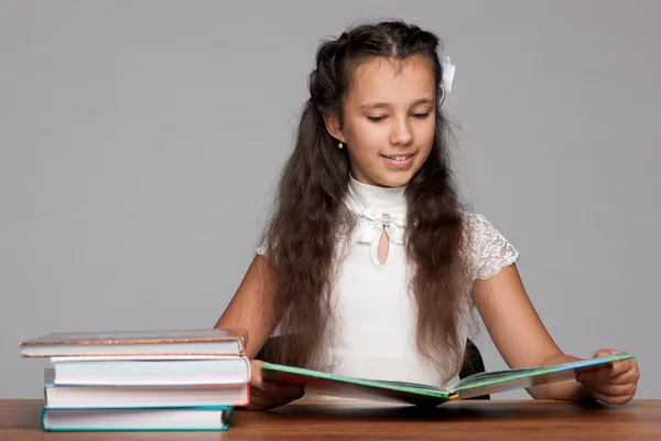 Giovane ragazza legge a tavola — Foto Stock