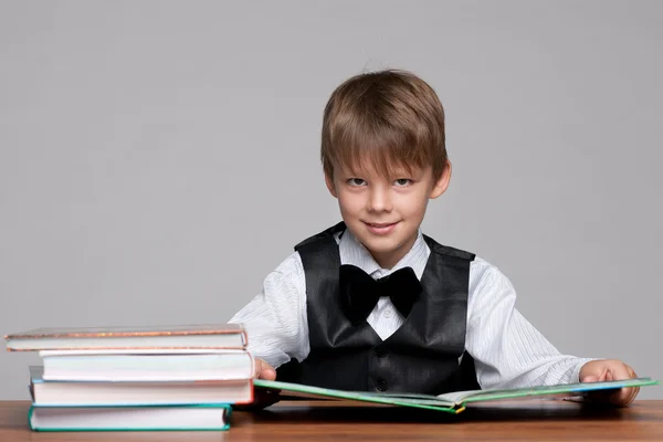 Молодий хлопчик за столом читає книгу — стокове фото