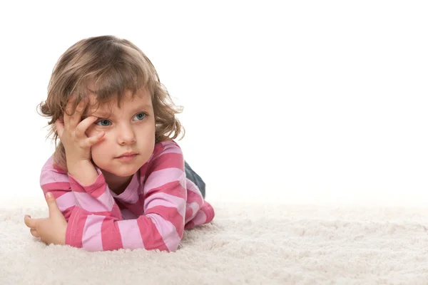 Nachdenkliches kleines Mädchen auf dem weißen Teppich — Stockfoto