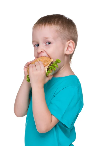 Cute little boy eats hamburger — Stock Photo, Image