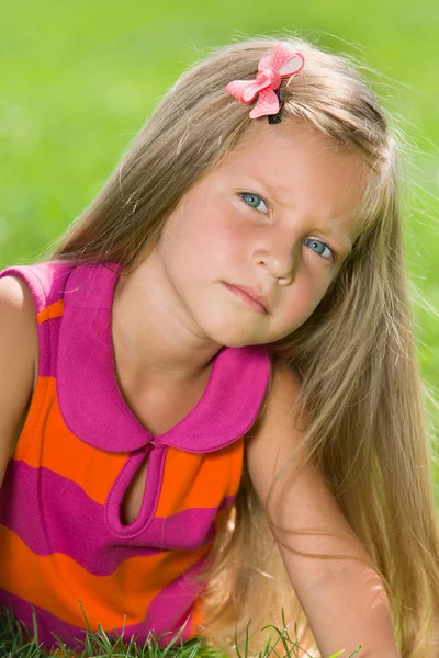 Allvarliga liten flicka på det gröna gräset — Stockfoto