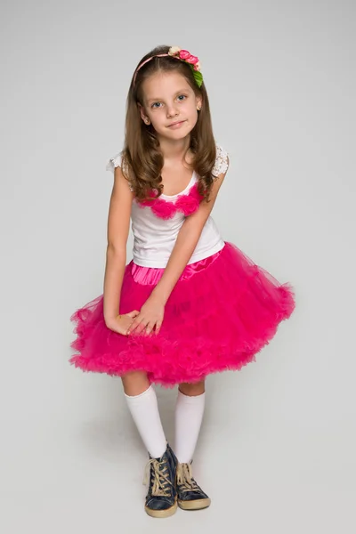 Klein meisje in een rode jurk tegen de grijze — Stockfoto
