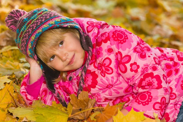 Thoughtful little girl on the yellow leaves — Stock Photo, Image