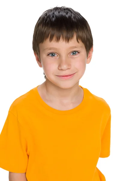 Улыбающийся мальчик в желтой рубашке стоит — стоковое фото