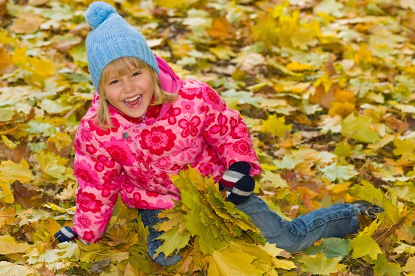 Ridendo bambina sulle foglie gialle — Foto Stock
