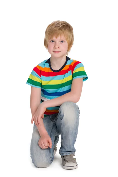 Schattige jongen in een gestreepte shirt zit — Stockfoto