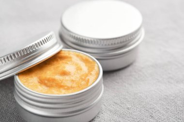 Keten kumaş üzerine iki kavanoz doğal kozmetik ürünü.