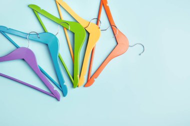 Mavi arka planda çok renkli elbise askıları var. Alışveriş ve satış kavramı.