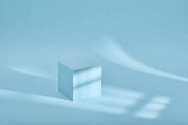 Gölgeli ve ışıklı ürün sunumu için mavi arkaplan. Boş kübik podyum. Model.