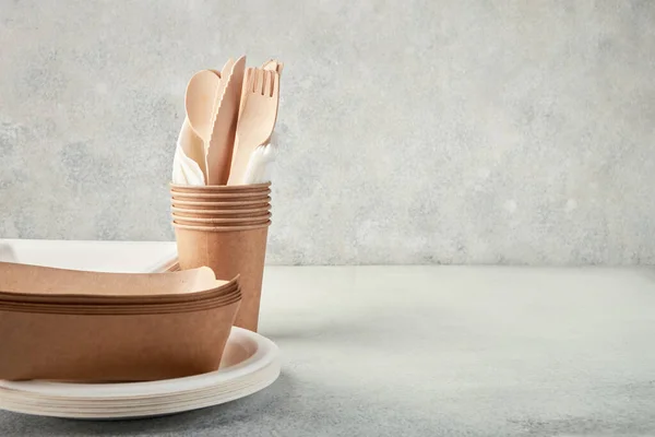 Biodegradable disposable tableware. Paper plates, cups, boxes. Wooden cutlery.