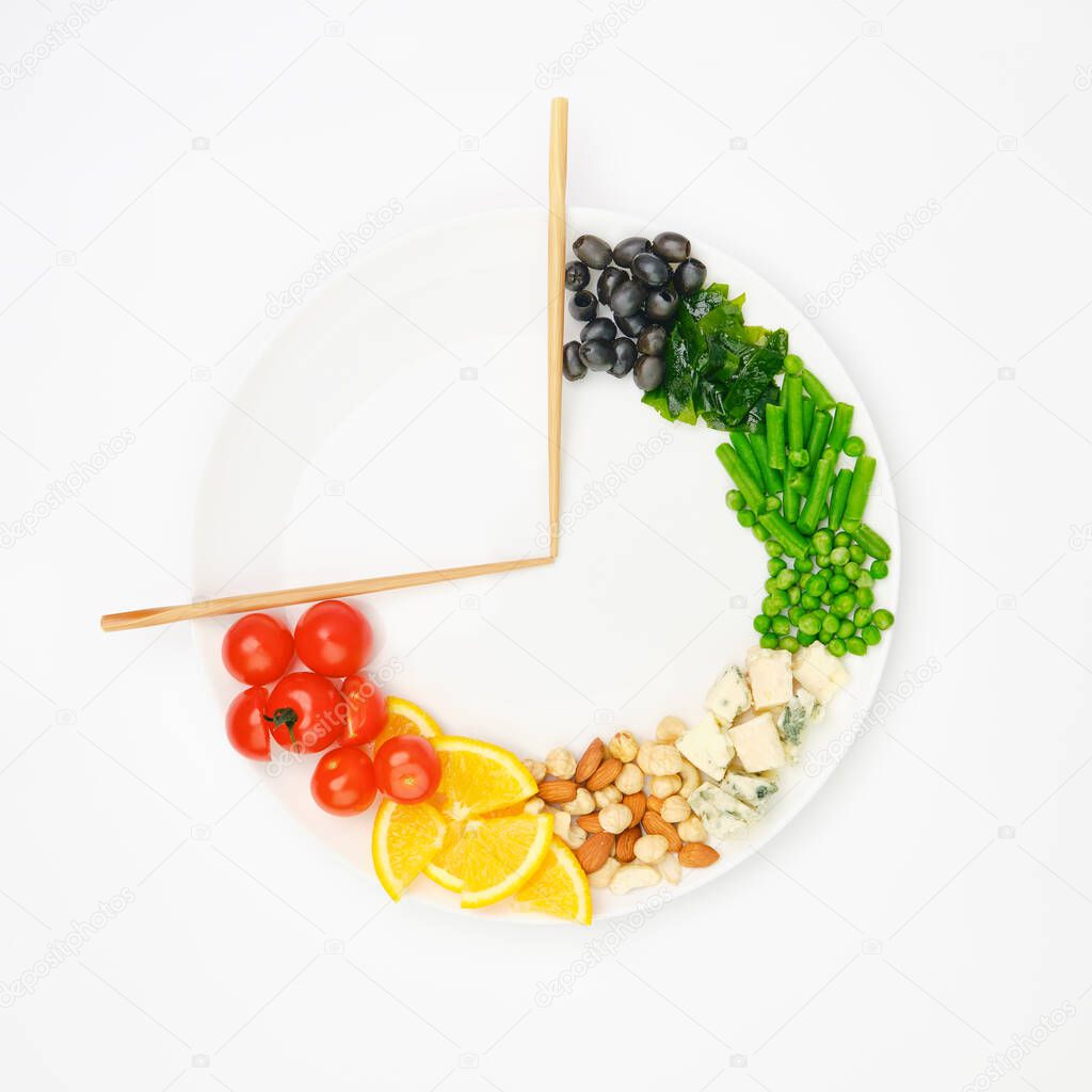 Colorful food and chopsticks arranged in the form of a clock on a plate. Intermittent fasting, diet, weight loss, lunch time concept.