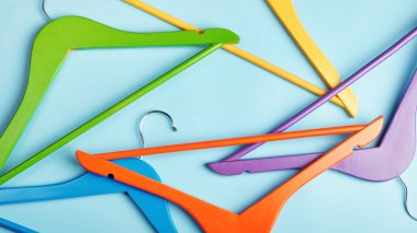 Mavi arka planda çok renkli elbise askıları var. Alışveriş ve satış kavramı.