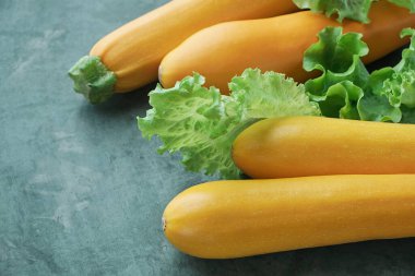 Mutfak masasında dört sarı kabak ve marul. Tamamen çiğ kabak.