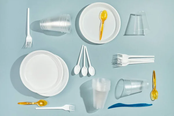 Disposable plastic tableware on blue background.