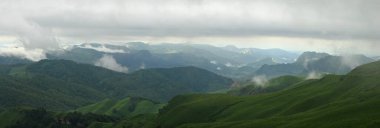 Rusya 'nın Kuzey Kafkasya Dağları. Rus doğası. Yeşil vadiler panoramik manzara. Bulutlarda ve siste.