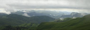 Rusya 'nın Kuzey Kafkasya Dağları. Rus doğası. Yeşil vadiler panoramik manzara. Bulutlarda ve siste.