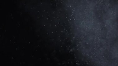 Siyah zemin üzerinde beyaz-gümüş parçacıkların havada asılı kalması. Bazı parçacıklar güzel bir bokeh içinde bulanıklaşıyor. Çeşitli karıştırma kiplerinde videolarınız için 4K arkaplan.