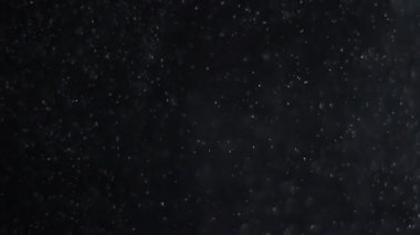 Siyah zemin üzerinde beyaz-gümüş parçacıkların havada asılı kalması. Bazı parçacıklar güzel bir bokeh içinde bulanıklaşıyor. Çeşitli karıştırma kiplerinde videolarınız için 4K arkaplan.