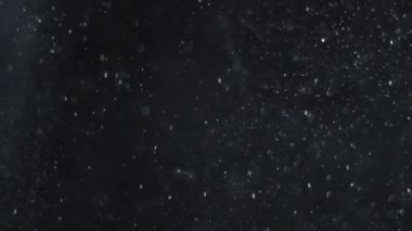 Siyah zemin üzerinde beyaz-gümüş parçacıkların havada asılı kalması. Bazı parçacıklar güzel bir bokeh içinde bulanıklaşıyor. Çeşitli karıştırma kiplerinde videolarınız için 4K arkaplan.