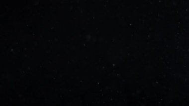 Siyah zemin üzerinde beyaz-gümüş parçacıkların havada asılı kalması. Bazı parçacıklar güzel bir bokeh içinde bulanıklaşıyor. Çeşitli karıştırma kiplerinde videolarınız için 4K arkaplan.