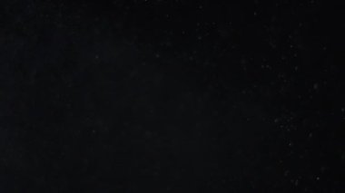 Siyah zemin üzerinde beyaz-gümüş parçacıkların havada asılı kalması. Bazı parçacıklar güzel bir bokeh içinde bulanıklaşıyor. Çeşitli karıştırma kiplerinde videolarınız için 4K arkaplan.
