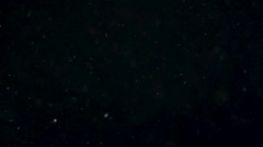 Siyah zemin üzerinde beyaz-gümüş parçacıkların havada asılı kalması. Bazı parçacıklar güzel bir bokeh içinde bulanıklaşıyor. Çeşitli karıştırma kiplerinde videolarınız için 4K arkaplan.