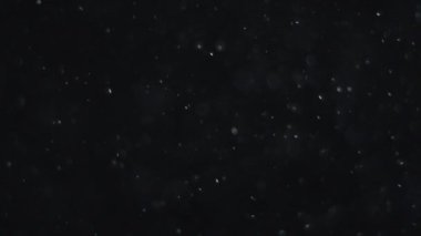 Siyah zemin üzerinde beyaz-gümüş parçacıkların havada asılı kalması. Bazı parçacıklar güzel bir bokeh içinde bulanıklaşıyor. Çeşitli karıştırma kiplerinde videolarınız için 4K arkaplan.
