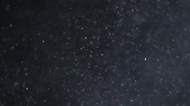 Siyah arka planda havada beyaz-gümüş parçacıkları var. Bazı parçacıklar güzel bir bokeh içinde bulanıklaşıyor. Çeşitli karıştırma kiplerinde videolarınız için 4K arkaplan.