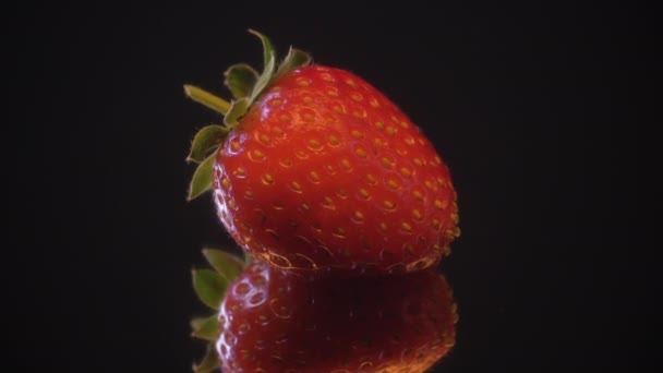 イチゴのマクロショット ビデオの360度の回転をループさせました 黒鏡を背景にスローモーション撮影 — ストック動画