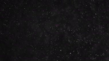 Siyah arka planda havada beyaz-gümüş parçacıkları var. Bazı parçacıklar güzel bir bokeh içinde bulanıklaşıyor. Çeşitli karıştırma kiplerinde videolarınız için 4K arkaplan.