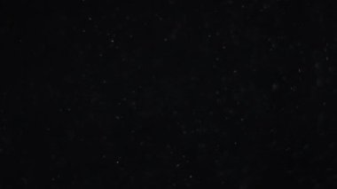 Siyah arka planda havada beyaz-gümüş parçacıkları var. Bazı parçacıklar güzel bir bokeh içinde bulanıklaşıyor. Çeşitli karıştırma kiplerinde videolarınız için 4K arkaplan.
