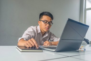 Asyalı genç adam iş yerinde uykulu ve yorgun hissediyor.