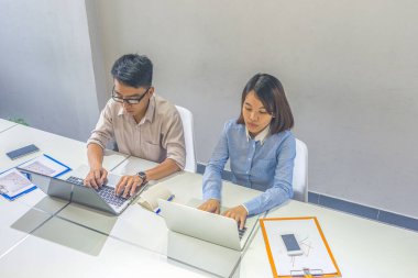 Ofiste dizüstü bilgisayarla çalışan Asyalı iş adamları.