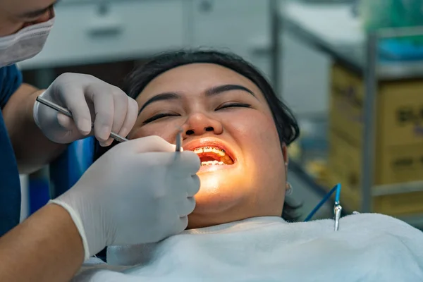 Foto de cerca del ortodoncista revisando los dientes de los aparatos ortopédicos para mujer — Foto de Stock