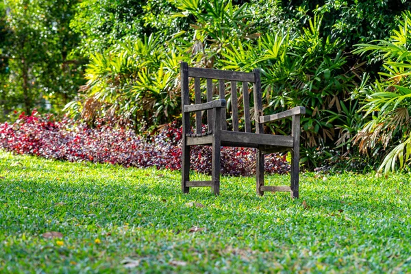 Рустик дерев'яний стілець на газоні з красивим садовим фоном — стокове фото
