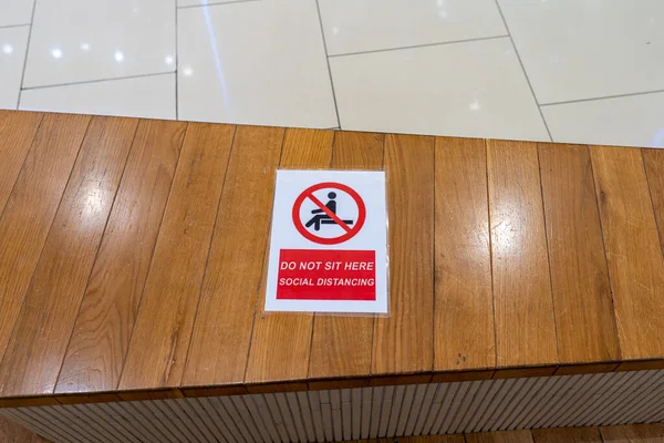 Sentado prohibición o señal de precaución a distancia social en el banco de madera —  Fotos de Stock