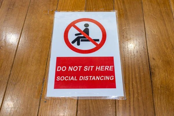 No sentarse y social signo de distanciamiento en el banco de madera — Foto de Stock