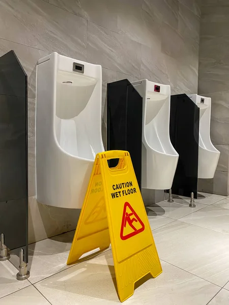 Mokra podłoga znak ostrożności w publicznej toalecie mężczyzn — Zdjęcie stockowe
