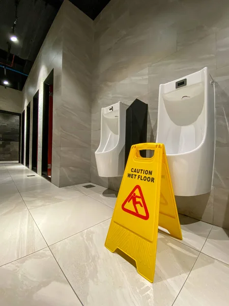 Mokra podłoga znak ostrożności w męskiej toalecie w hotelu — Zdjęcie stockowe