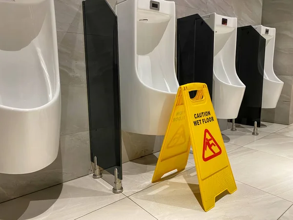 Żółta mokra podłoga znak ostrożności po sprzątaniu w publicznej męskiej toalecie — Zdjęcie stockowe