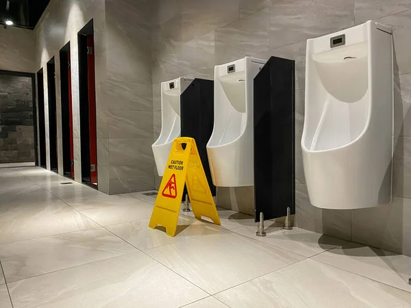 Żółty znak mokra podłoga podczas czyszczenia w toalecie publicznej mężczyzn — Zdjęcie stockowe