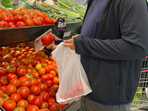Grasso uomo utilizzando sacchetto di bioplastica selezionando pomodori al negozio di alimentari — Foto Stock